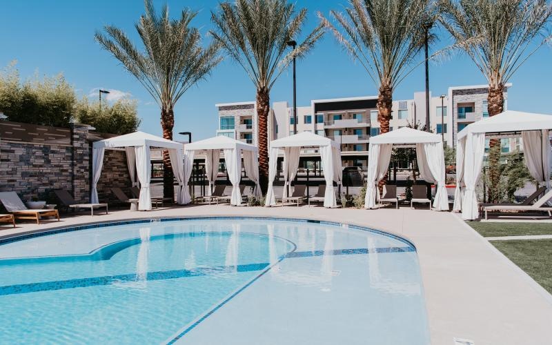 a pool with white chairs and white umbrellas next to a building